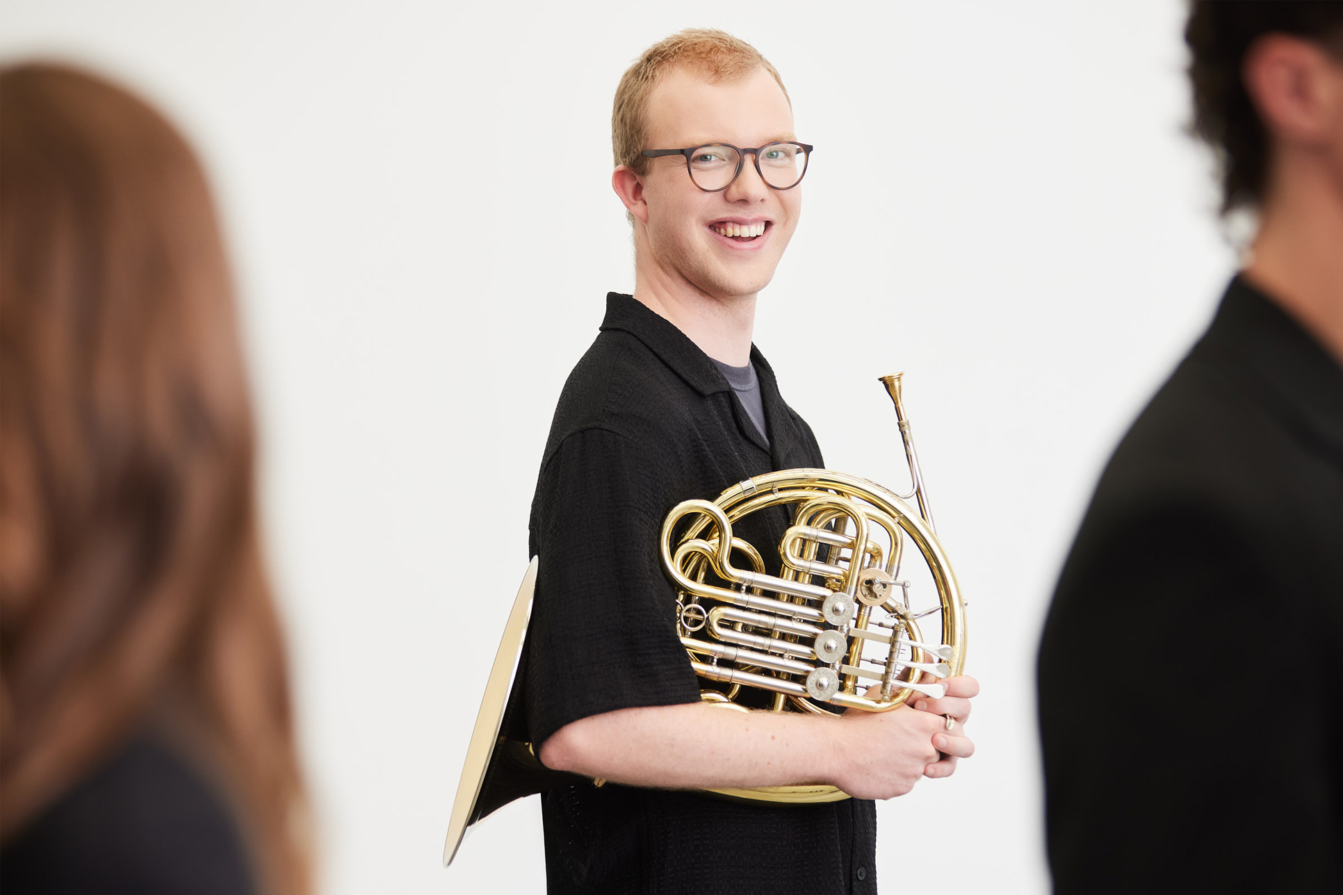  A man holding a French horn smiling.